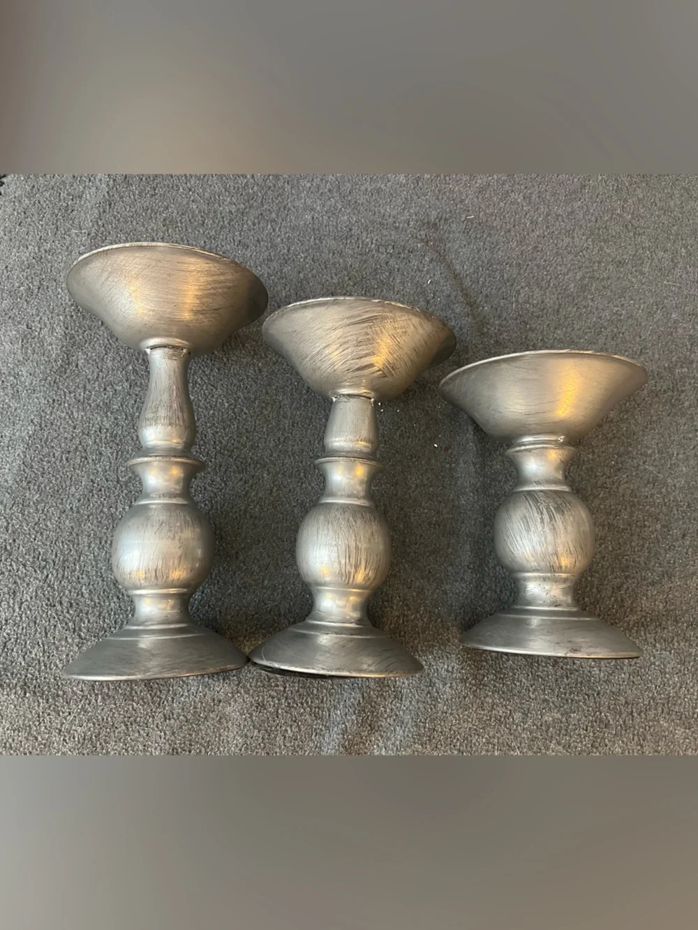 set of three silver-tone metal candlestick holders features a graduated design
